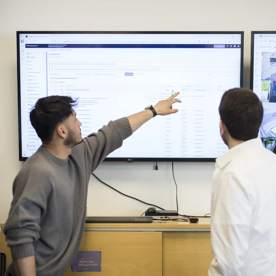 Zwei Kollegen vor den Security- und Kamera-Dashboards